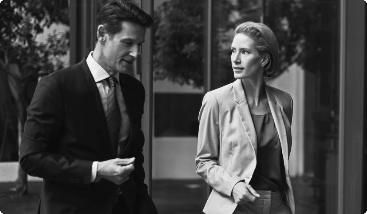 Two well-dressed colleagues walk out of an office building