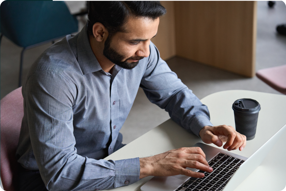 Person with coffee typing on laptop