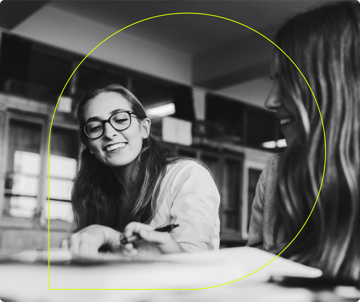 A person wearing glasses smiles in a library.