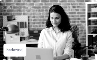 A woman works on a computer beside the HackerOne logo