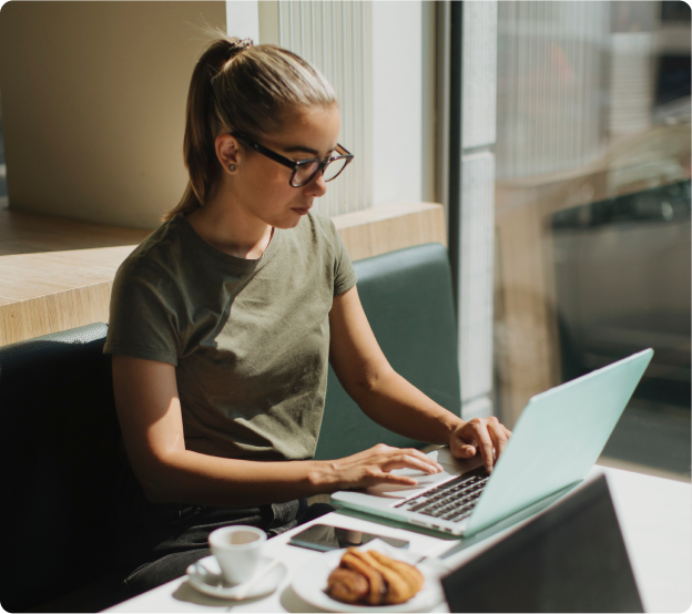 Person with glasses and ponytail working on laptop