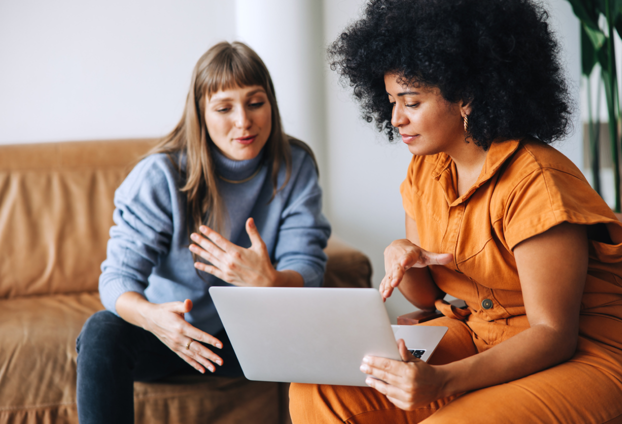 Two people talking in front of laptop