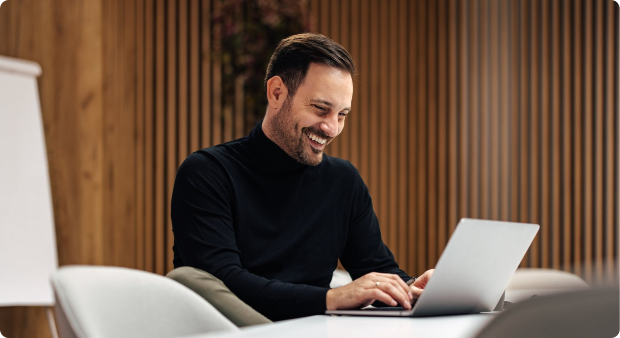Person smiling at laptop in conference room