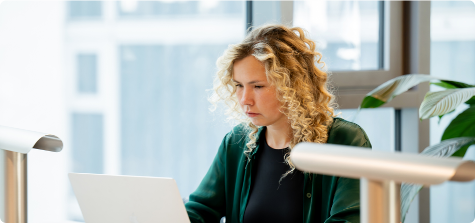 An employee works at a desk beside a large window.